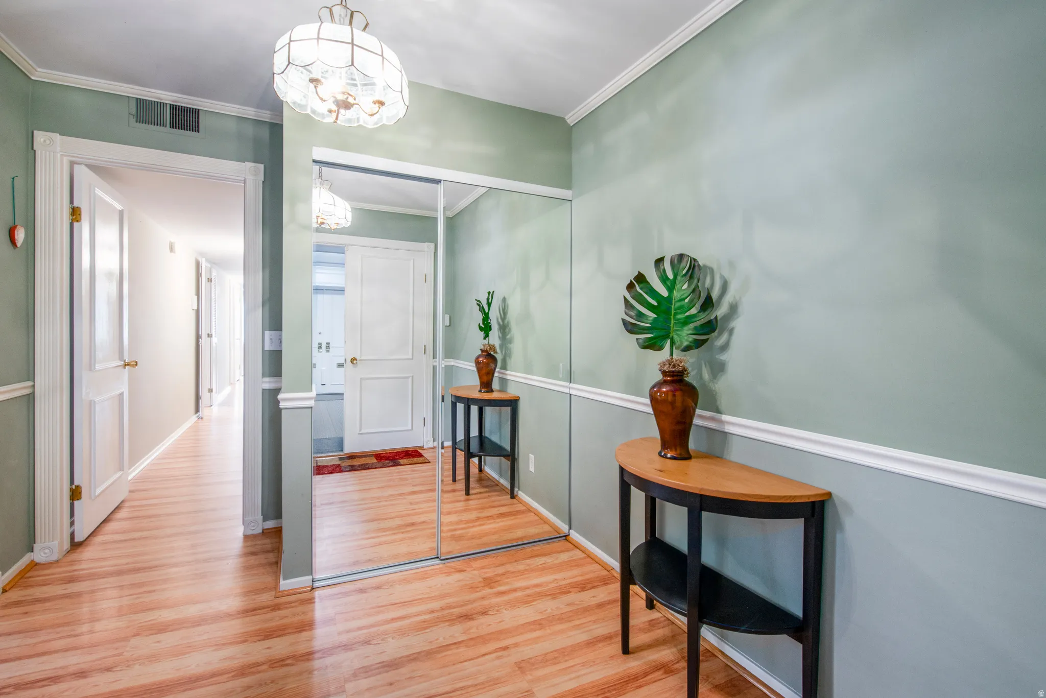 Entryway with hanging lights, wood finished floors, and crown molding