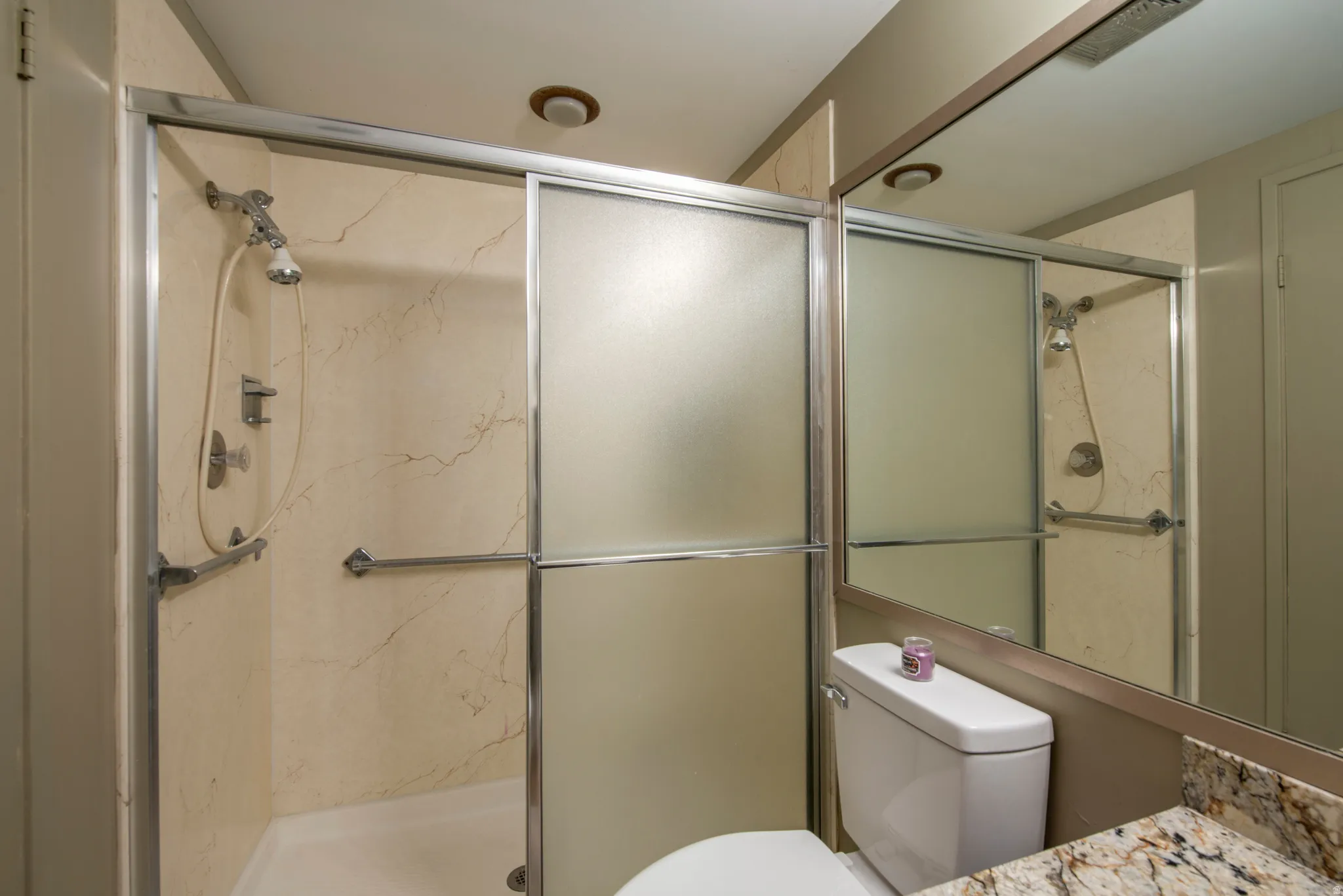 Full bath featuring vanity and a marble finish shower