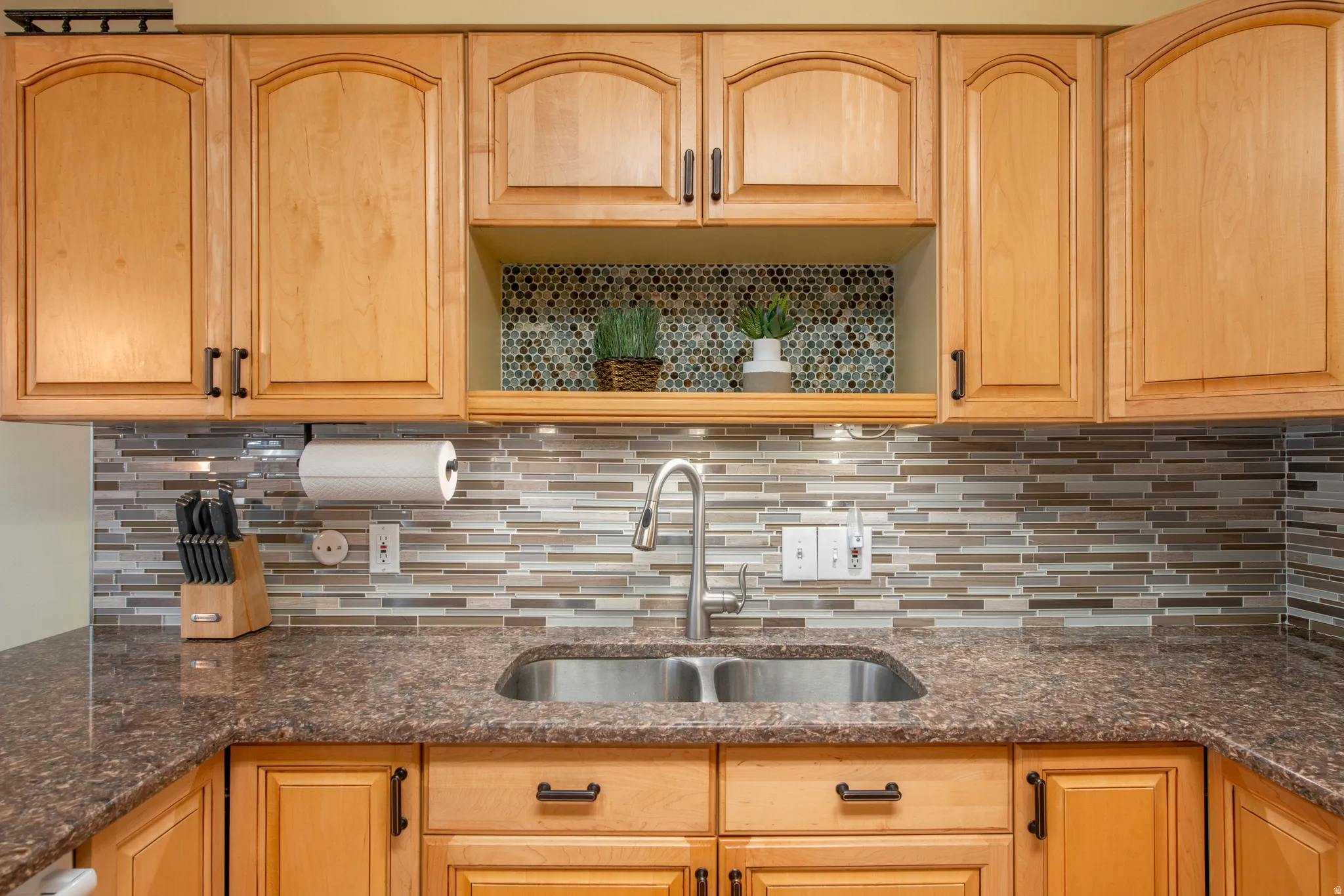 Kitchen with dark stone countertops and light wood finish cabinetry