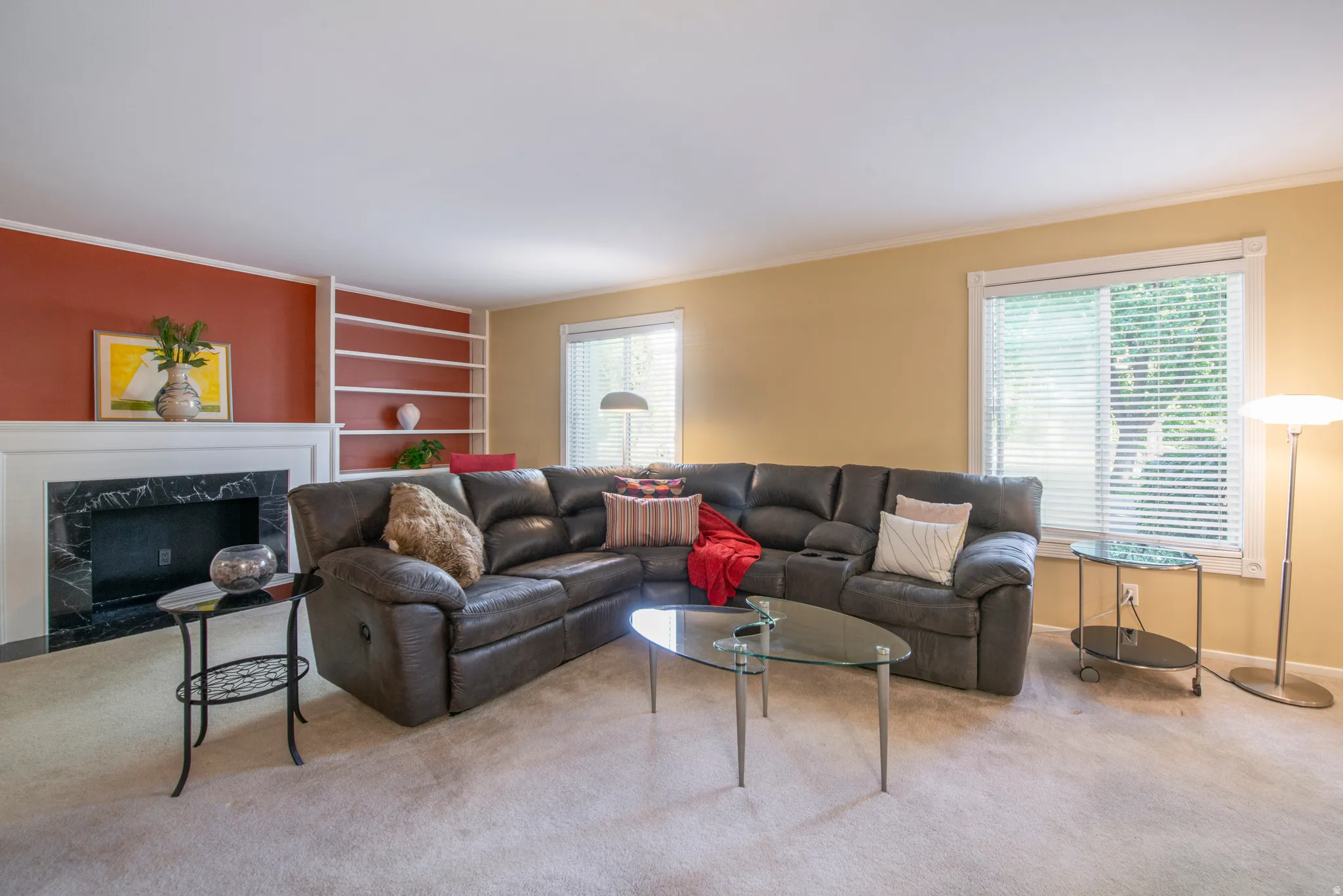 Carpeted living area featuring a fireplace, plenty of natural light, built in shelves, and ornamental molding