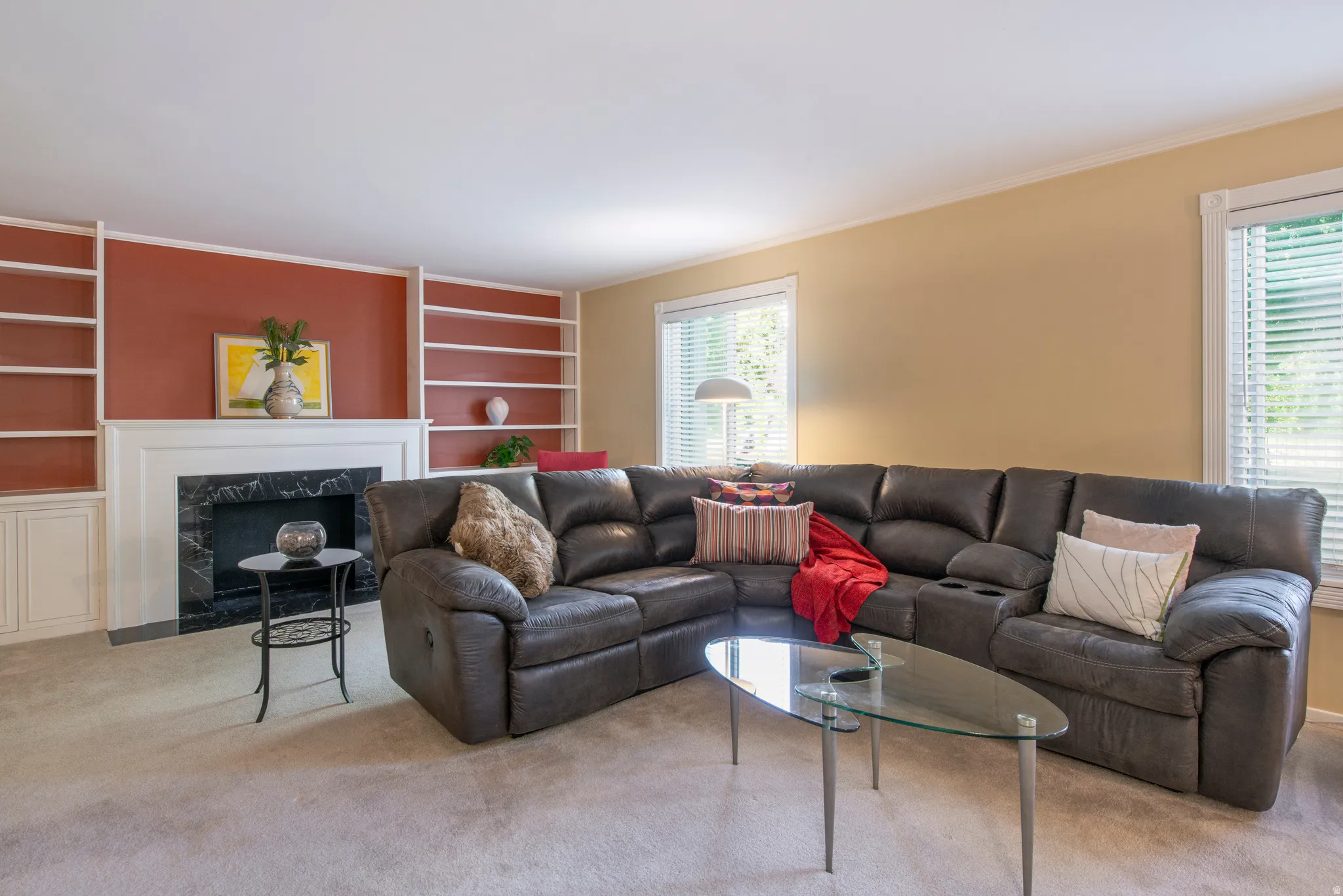 Carpeted living room with built in features, plenty of natural light, a fireplace, and ornamental molding