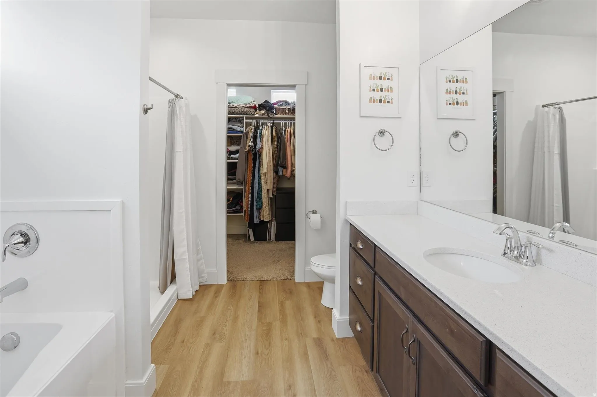 Bathroom with a garden tub, a stall shower, vanity, and light wood-type flooring