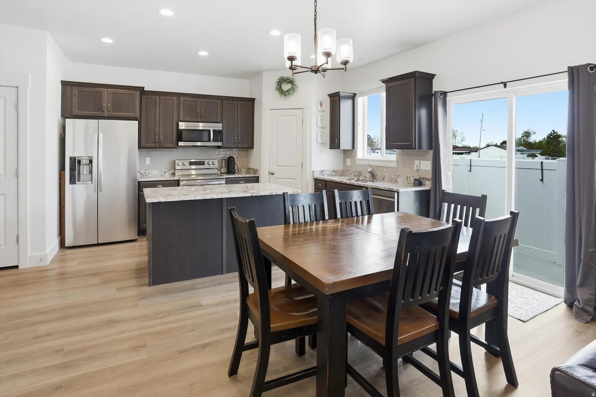 Dining room with light wood-style flooring and suspended lighting