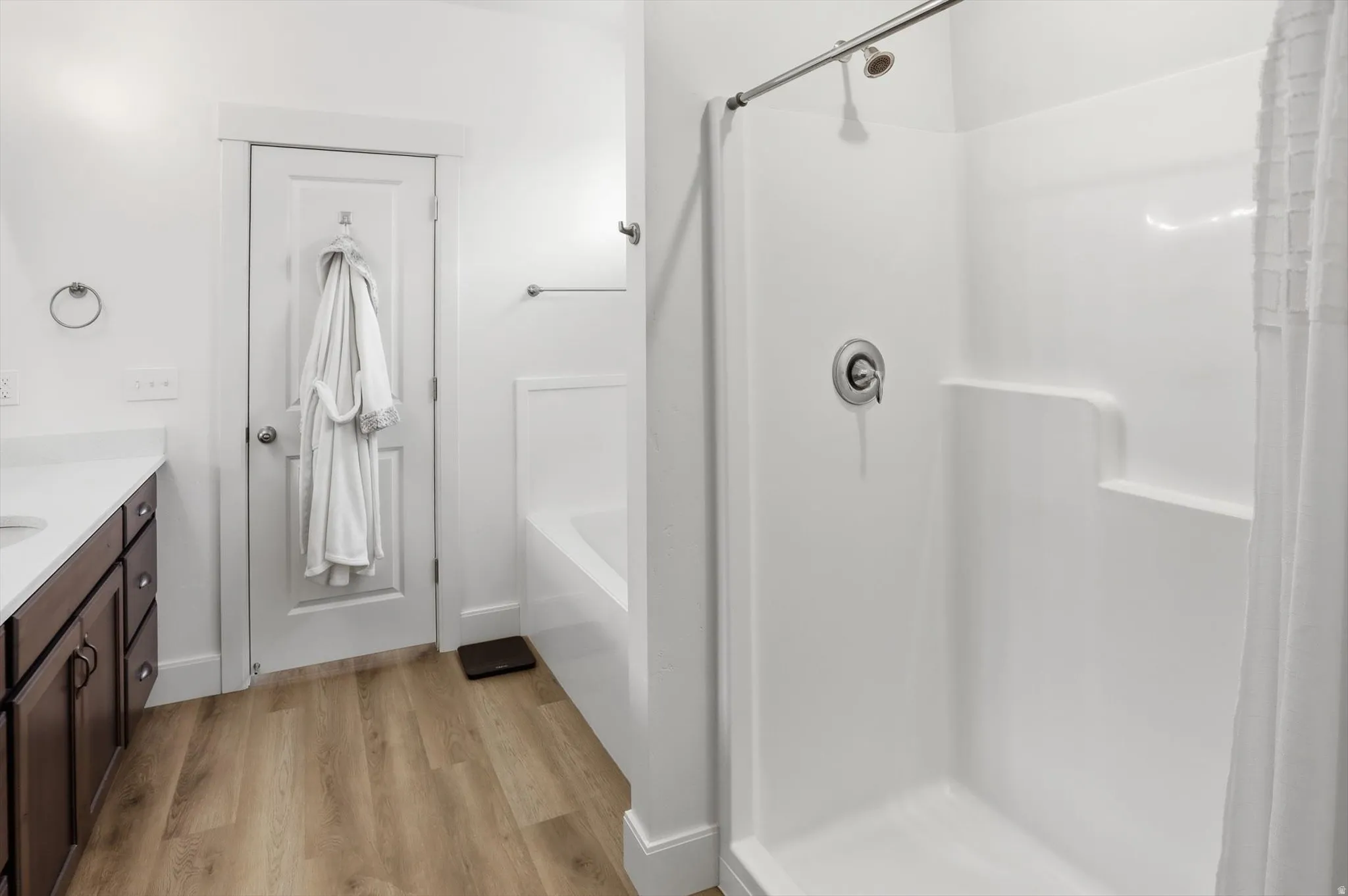 Full bathroom with vanity, a shower stall, light wood-style floors, and a bath