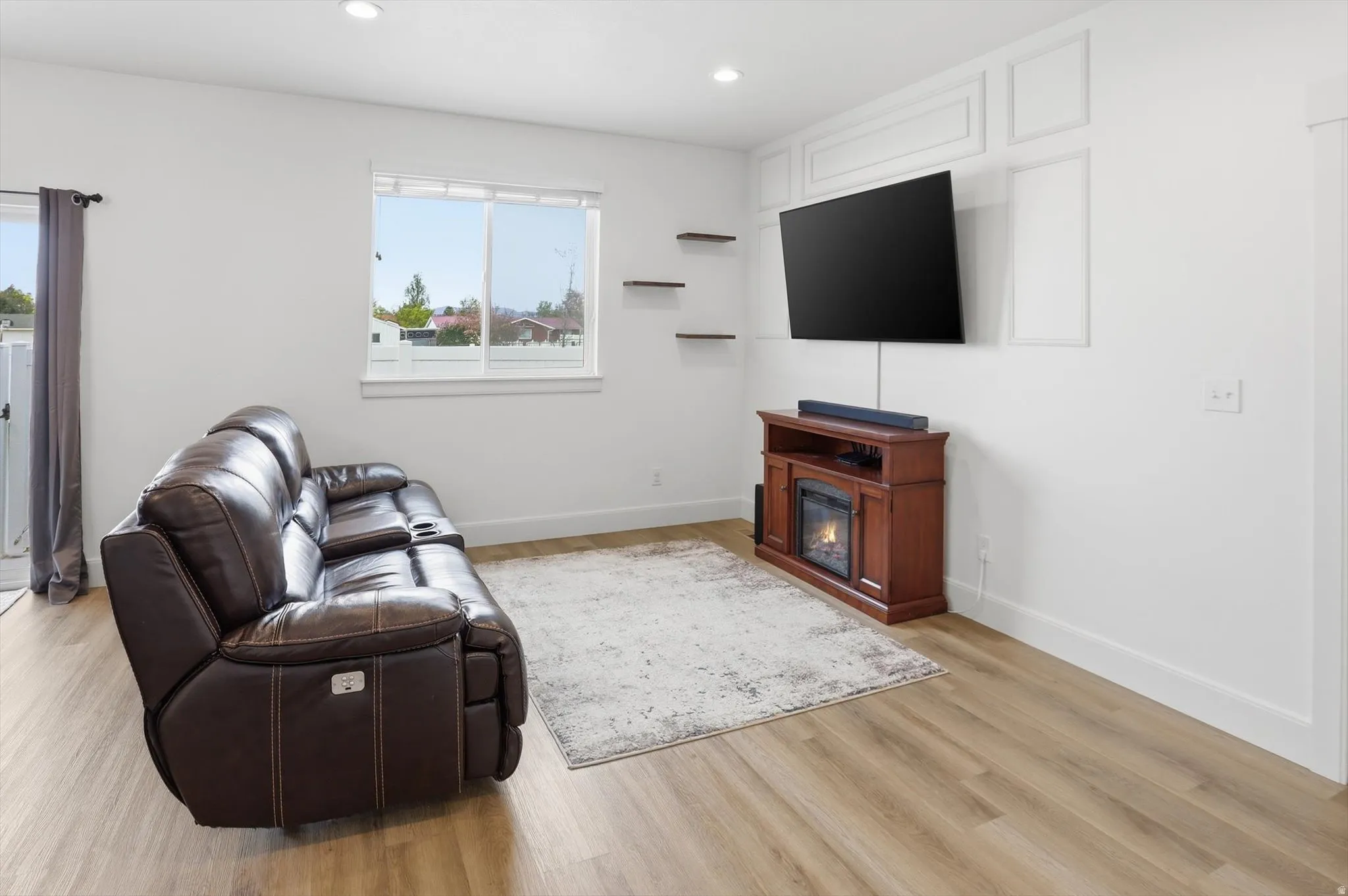 Living room featuring light wood-style floors, recessed lighting, and a glass covered fireplace