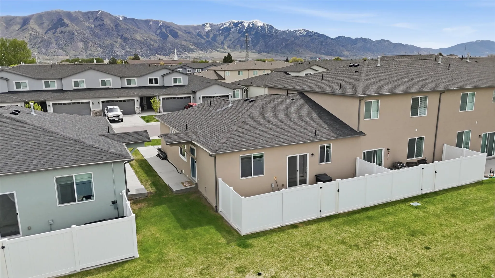 Rear view of property with stucco siding, a mountain view, a fenced backyard, and roof with shingles