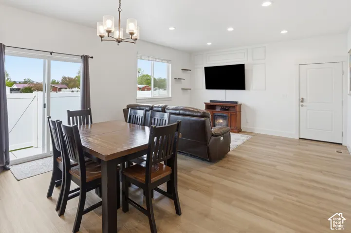 Open-concept interior featuring wood-finish flooring, recessed lighting, a chandelier, wall-panel detailing, and a sliding glass door