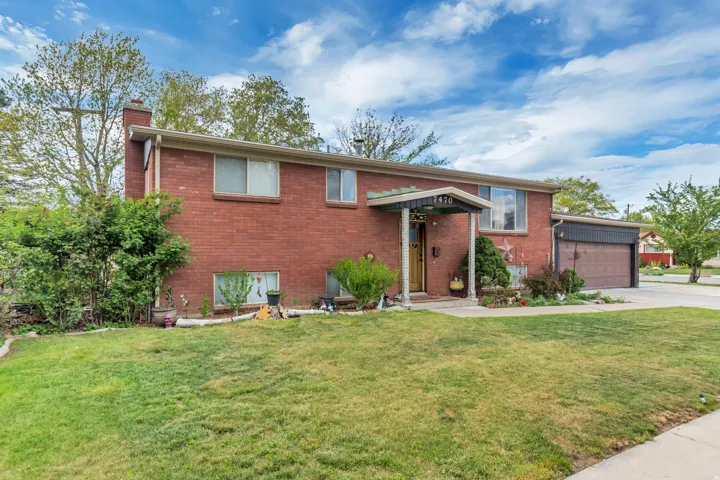 Split foyer home featuring a front yard, a chimney, brick siding, concrete driveway, and an attached garage