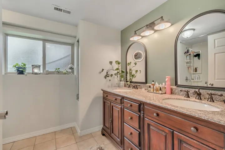 Full bathroom with double vanity, light tile patterned floors, and a tub and shower