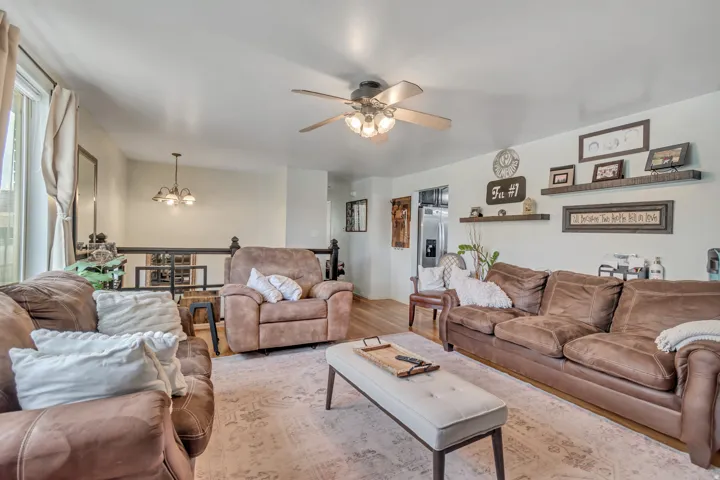 Living area featuring a ceiling fan, suspended lighting, and wood finished floors