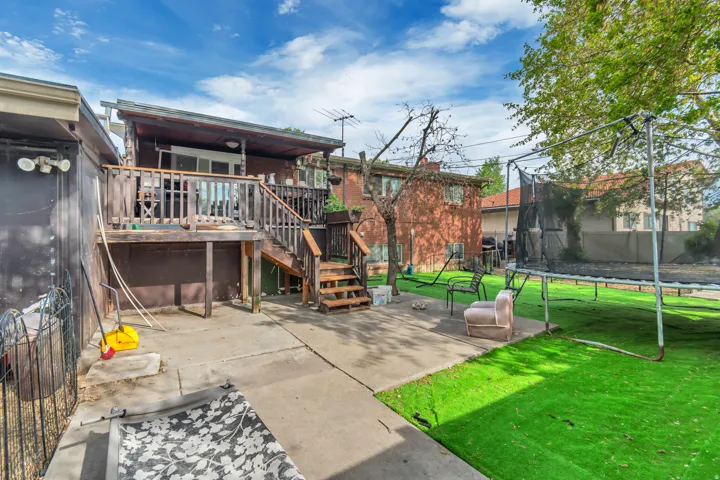 Rear view of property with a trampoline, a deck, and a patio area
