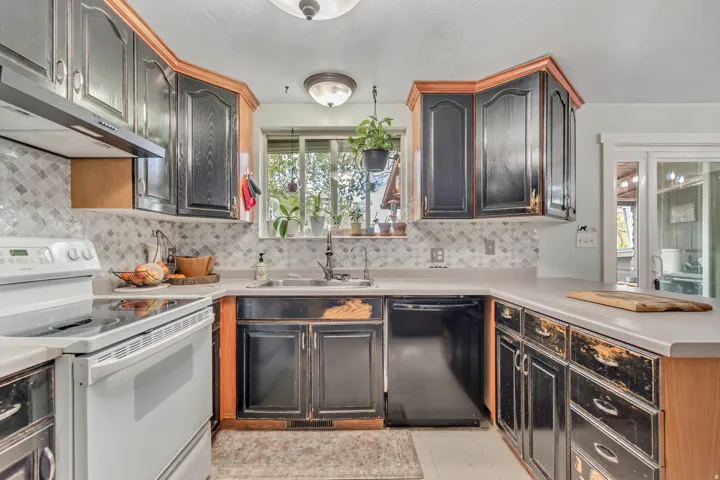 Kitchen featuring electric range, dishwasher, light countertops, a peninsula, and light tile patterned floors