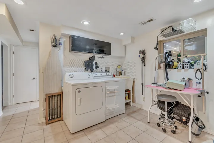 Laundry room with light tile patterned flooring, washer and clothes dryer, and cabinet space
