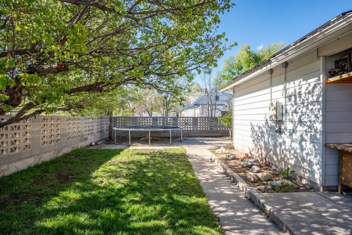 Fenced backyard featuring a trampoline