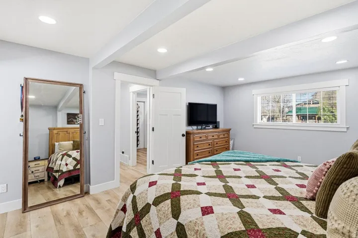 Bedroom featuring light wood-style floors, recessed lighting, and beamed ceiling