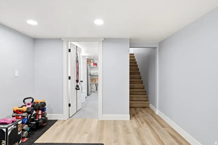 Finished below grade area featuring light wood-style floors, recessed lighting, and freestanding refrigerator