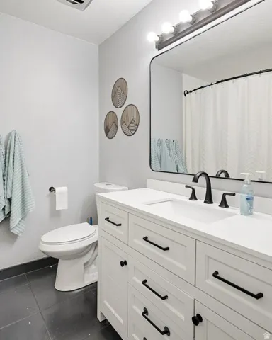 Bathroom featuring vanity, dark tile patterned floors, and curtained shower