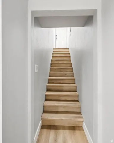 Stairway with wood finished floors and baseboards