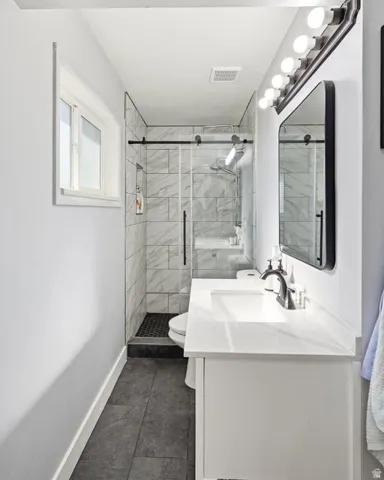 Full bathroom with vanity, a shower stall, and dark tile patterned flooring