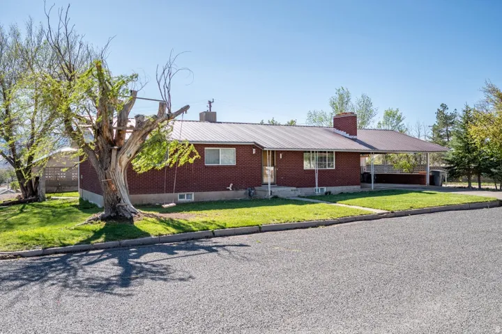 Ranch-style home featuring a metal roof, a chimney, a front lawn, and an attached carport