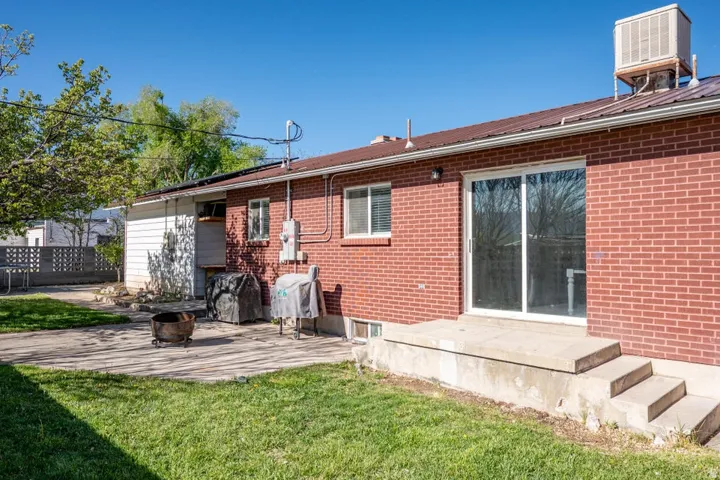 Rear view of property featuring brick siding, a patio, a yard, and a metal roof