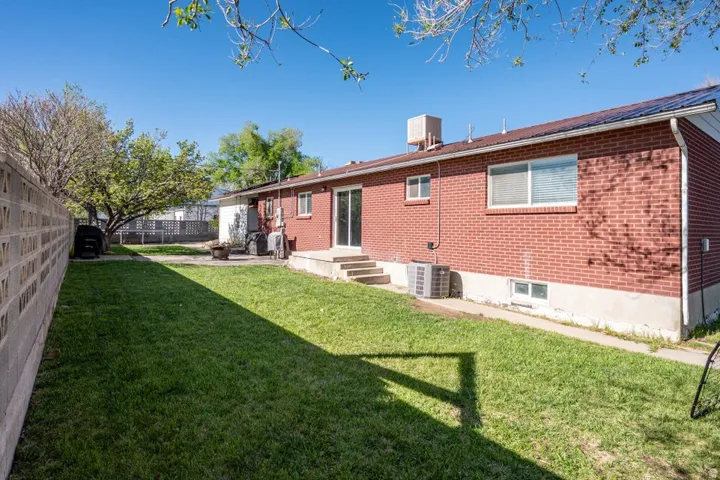 Rear view of property featuring brick siding, a fenced backyard, and entry steps