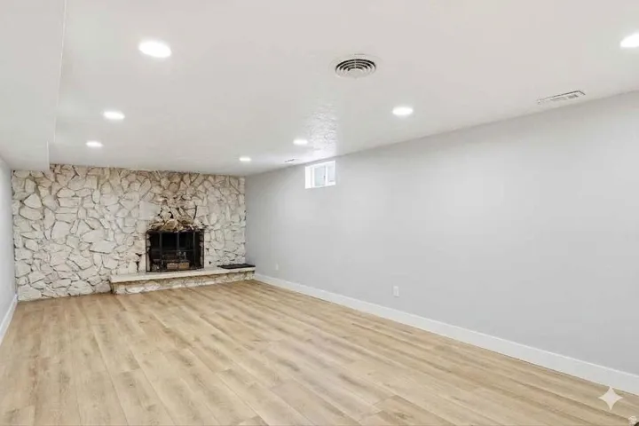 Unfurnished living room with a stone fireplace, light wood-style floors, and recessed lighting
