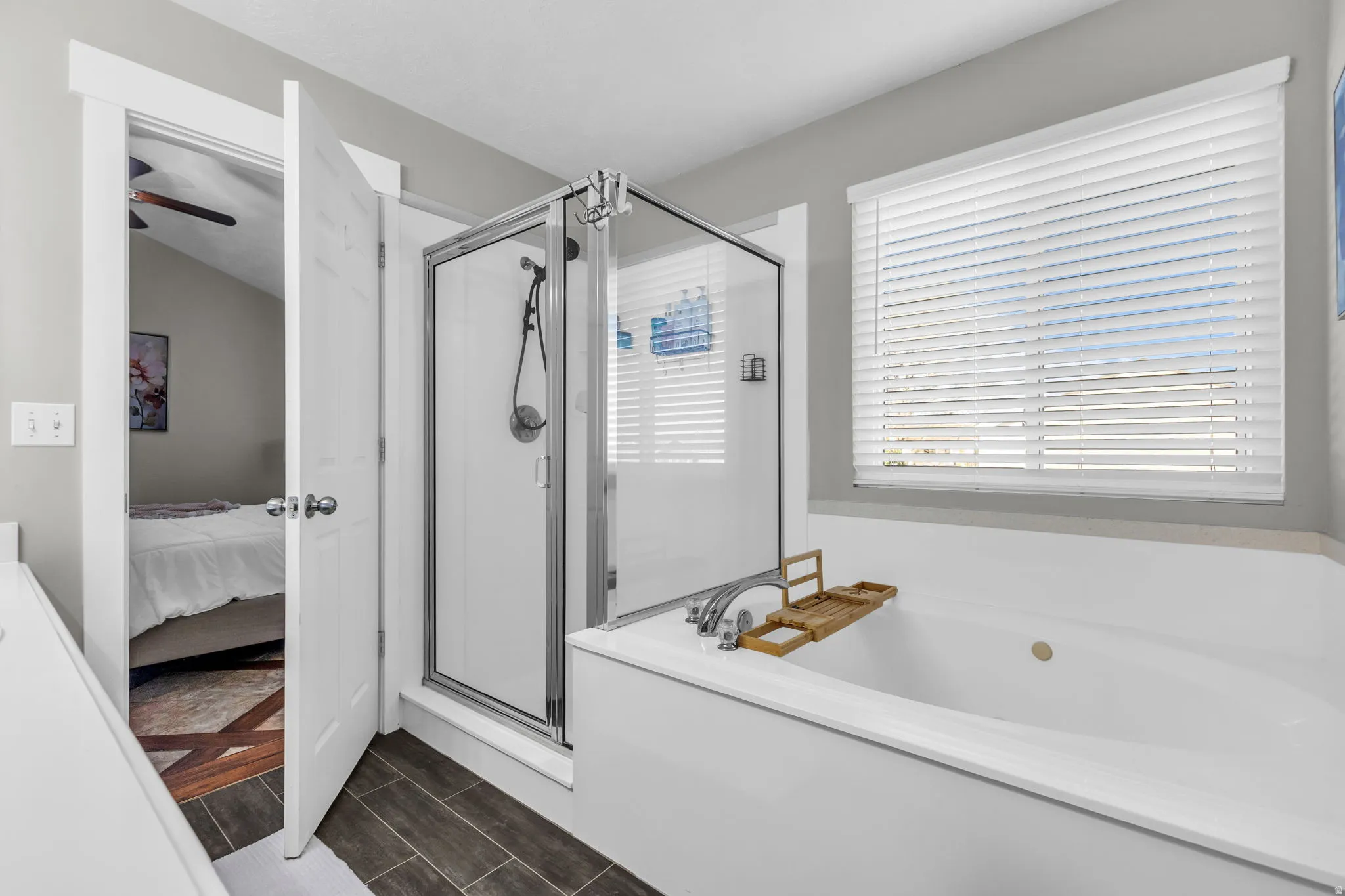 Full bath with a shower stall, connected bathroom, a garden tub, and wood finish floors