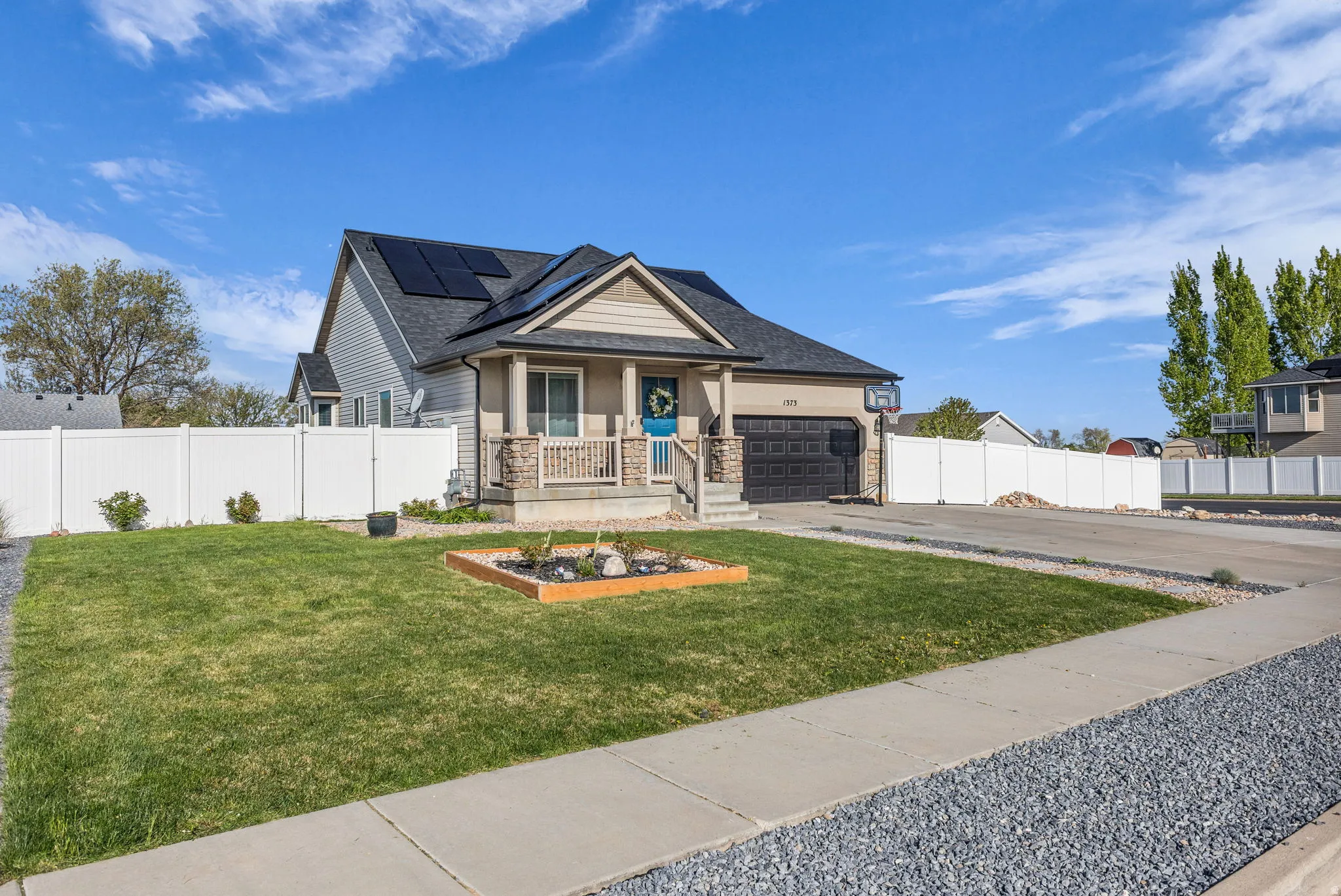 Craftsman-style house with covered porch, a garage, asphalt driveway, roof mounted solar panels, and stone siding