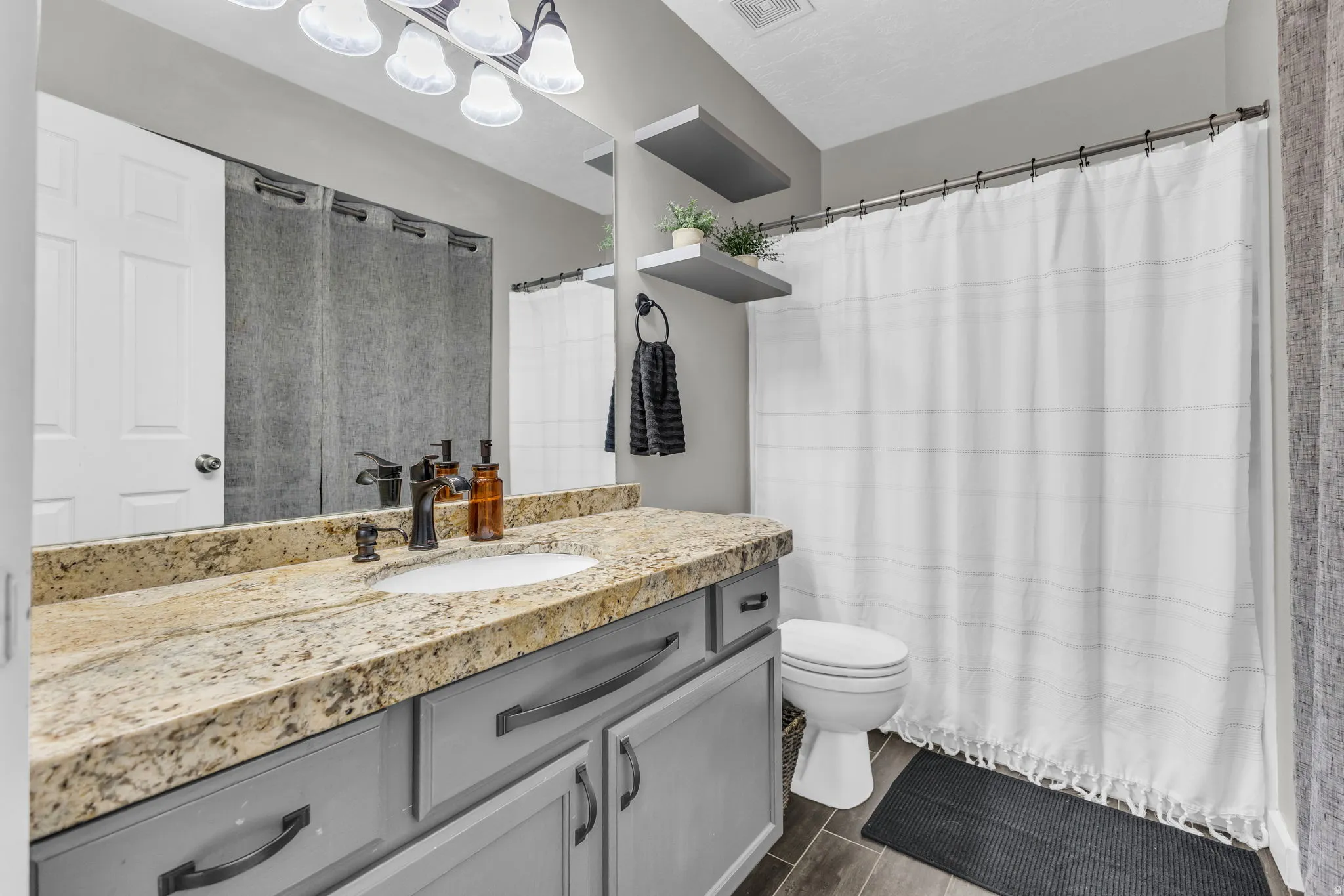 Full bathroom with vanity, curtained shower, and wood tiled floors