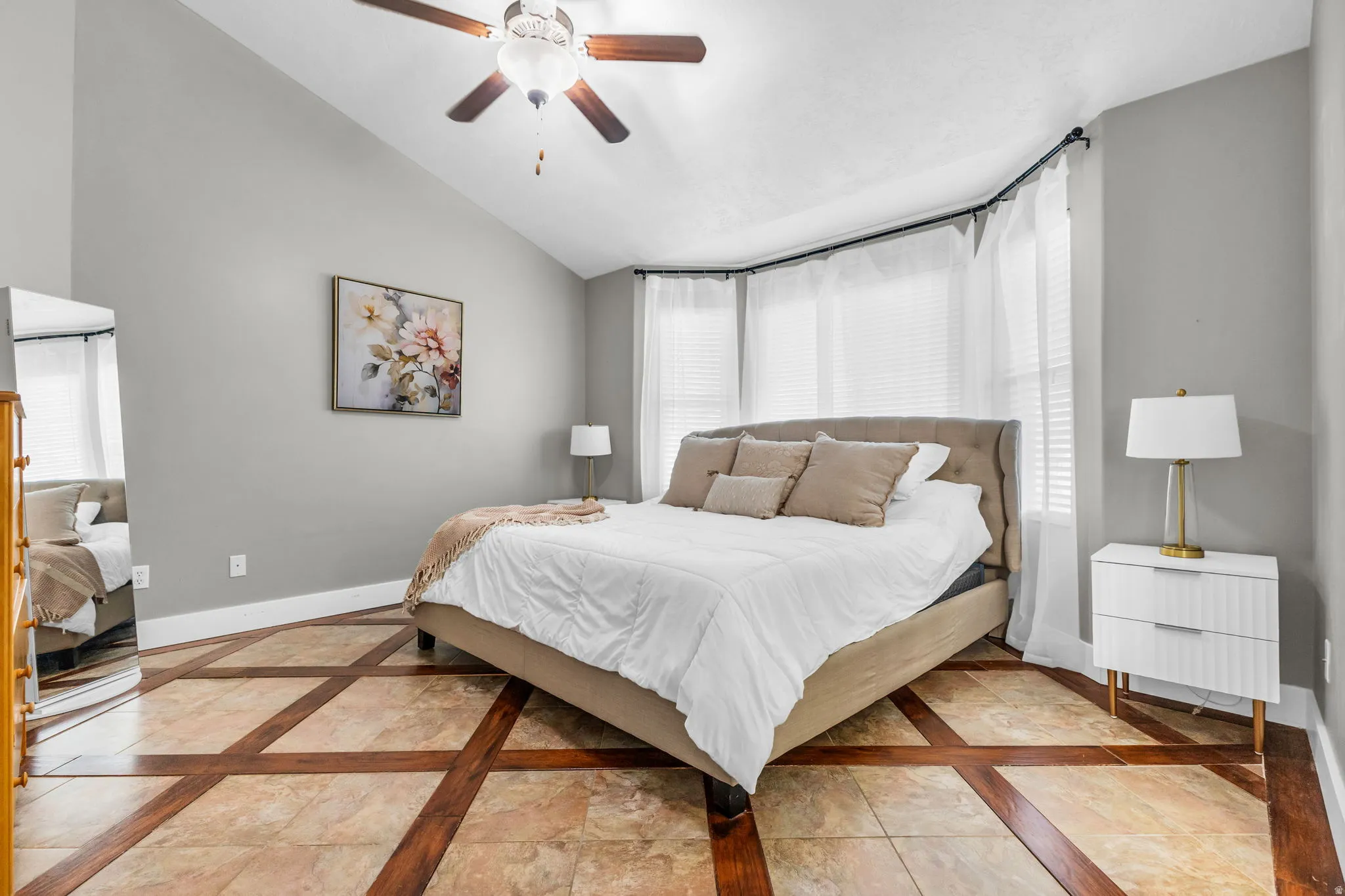 Bedroom featuring inlaid floor details, lofted ceiling, and a ceiling fan