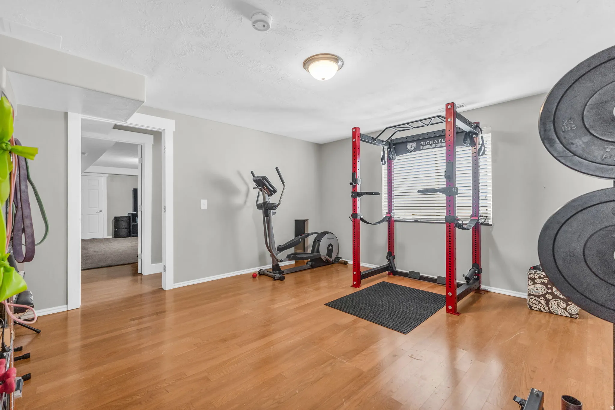 Workout area featuring light wood-type flooring and a textured ceiling