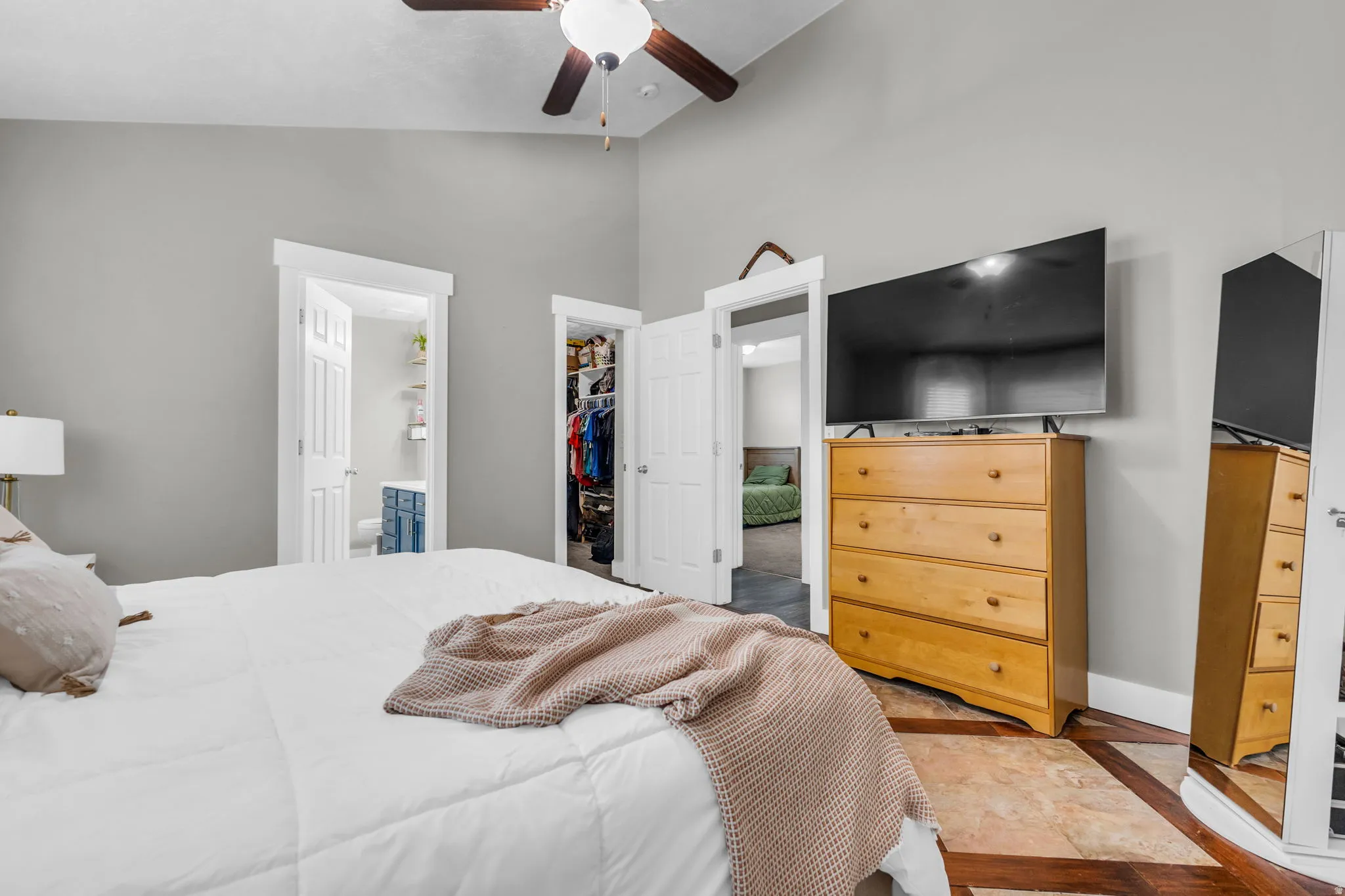 Bedroom with ensuite bathroom, lofted ceiling, a spacious closet, and ceiling fan