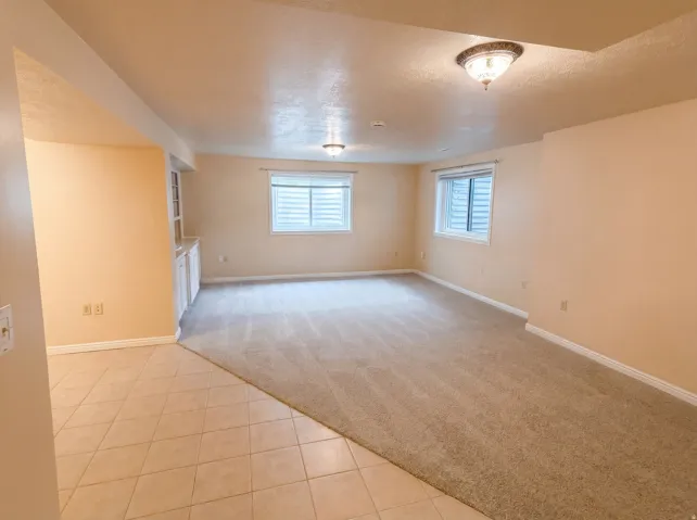 Unfurnished living room featuring light colored carpet, light tile patterned floors, and a textured ceiling