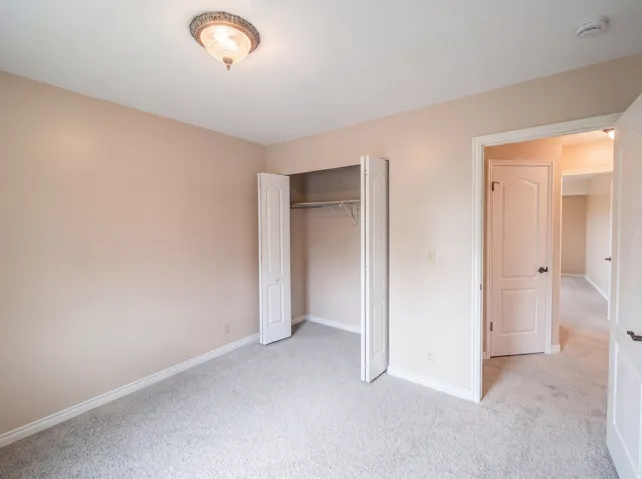 Unfurnished bedroom featuring light carpet and a closet