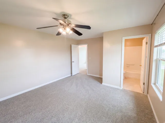 Unfurnished bedroom featuring light colored carpet, ceiling fan, and ensuite bathroom