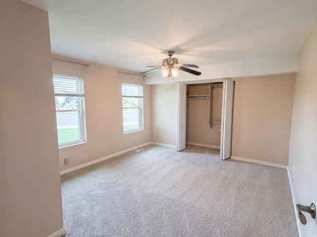 Unfurnished bedroom with a closet, light carpet, and a ceiling fan