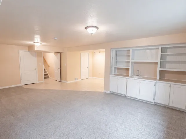 Unfurnished living room featuring light carpet and baseboards