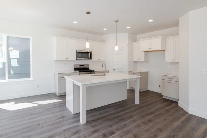 White cabinetry, stainless steel appliances, white subway tile backsplash, white countertop, and wood-finish flooring