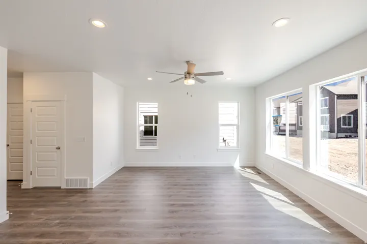 Spacious room featuring wood-finish flooring, ample windows, recessed lighting, a ceiling fan, and white paneled doors