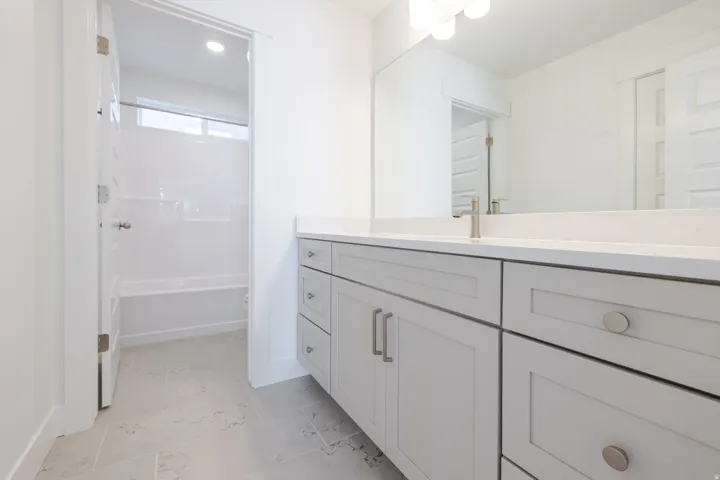 Dual vanity with light-colored cabinetry, polished chrome hardware, and a solid surface countertop