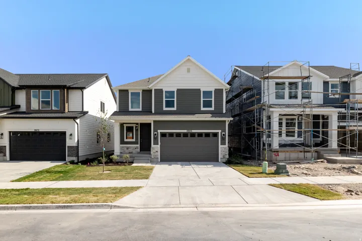 Contemporary exterior with dark siding, white trim, attached two-car garage, concrete driveway, and front lawn