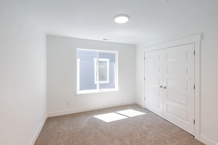 Recessed lighting, white walls, carpeted flooring, a window, and paneled bifold doors