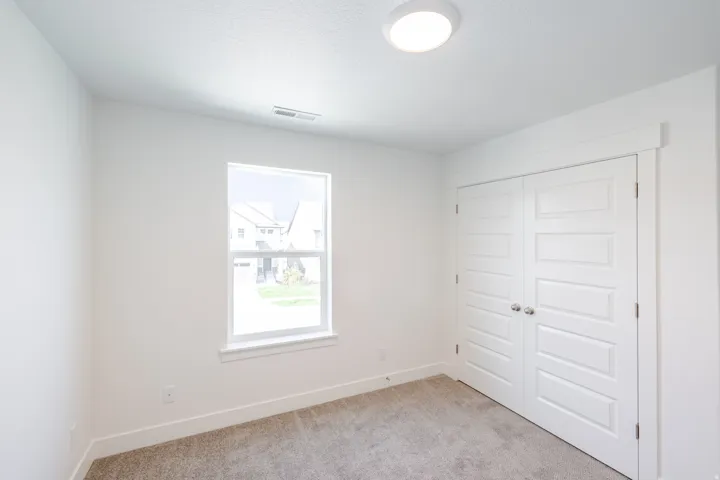 Plush carpeting, clean white walls, and a window with white trim