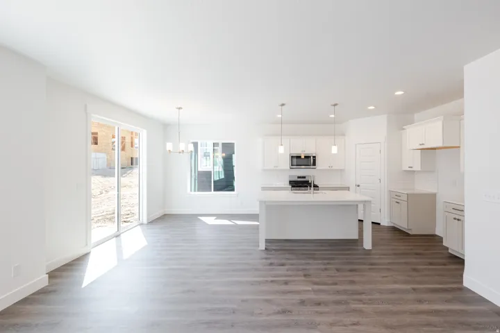 Open-concept living area with wood-finish flooring, white walls, and a sliding glass door