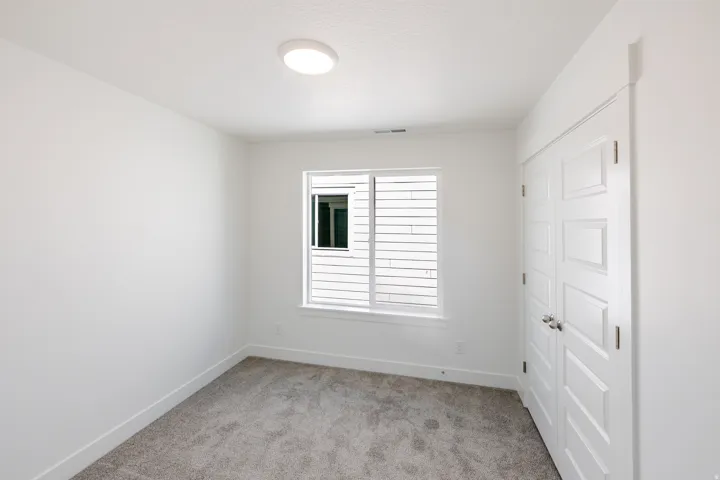 Neutral wall paint, plush carpet flooring, recessed ceiling light, paneled closet doors, and a window with horizontal blinds