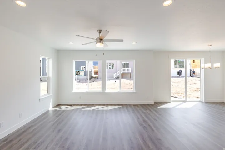 Spacious room with wood-finish flooring, recessed lighting, ceiling fan, and multiple windows
