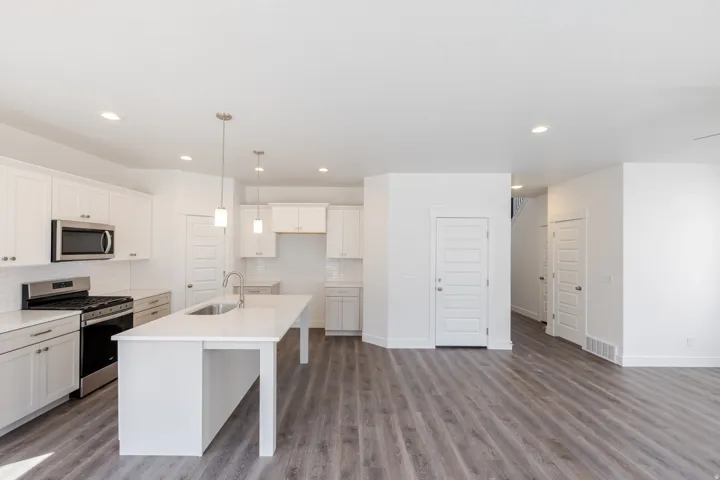 Kitchen with white shaker cabinetry, stainless steel appliances, white subway tile backsplash, a large island with sink, and pendant lighting