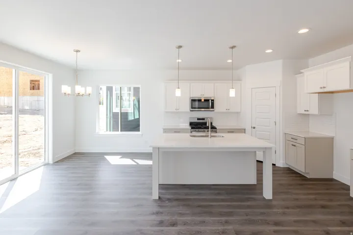 White kitchen cabinetry, stainless steel appliances, solid surface countertops, a center island, and wood-finish flooring