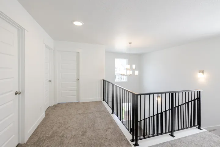 Upper level landing featuring neutral carpet, recessed lighting, and a modern chandelier